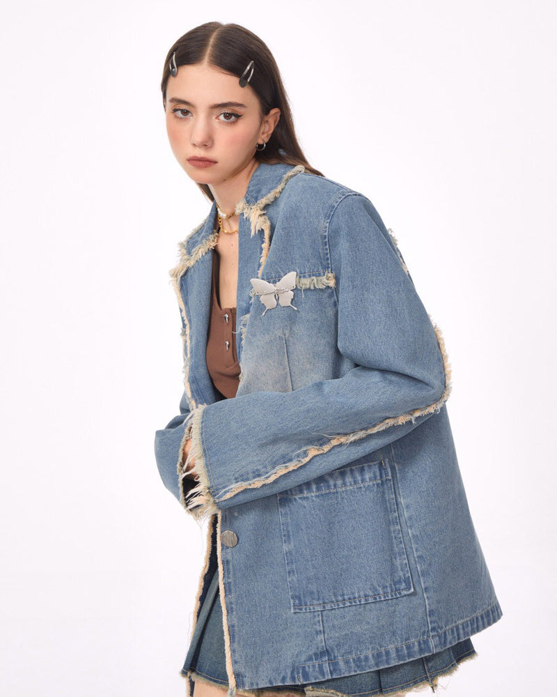 A distressed denim blazer featuring a charming butterfly pin and frayed edges. This jacket includes large front pockets and a lapel collar, perfect for adding a vintage and grunge touch to any outfit