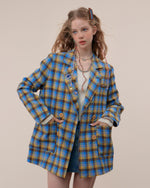 The Oversized Preppy-Style Plaid Blazer features a vibrant blue and yellow plaid pattern. Its double-breasted style and roomy fit make it ideal for layering over any look