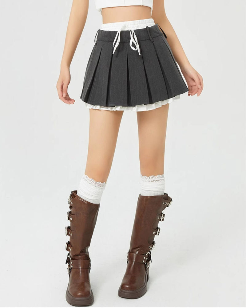 This layered preppy skirt features pleated detailing with a contrast lace underskirt. The ribbon waist and layered construction give it a playful, school-girl vibe- boogzel clothing