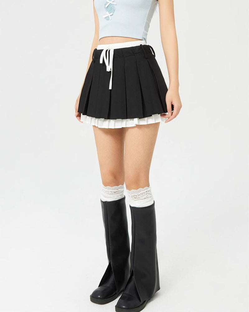 This layered preppy skirt features pleated detailing with a contrast lace underskirt. The ribbon waist and layered construction give it a playful, school-girl vibe- boogzel clothing