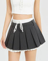 This layered preppy skirt features pleated detailing with a contrast lace underskirt. The ribbon waist and layered construction give it a playful, school-girl vibe- boogzel clothing