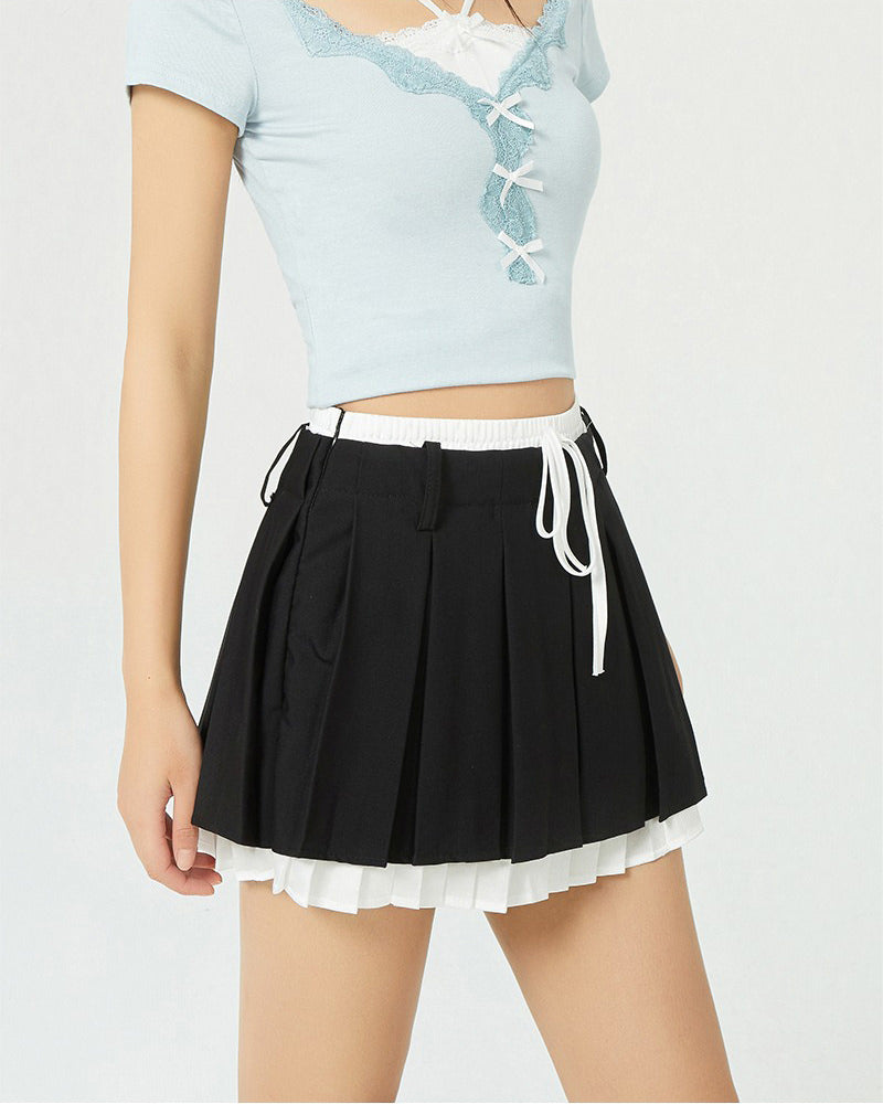 This layered preppy skirt features pleated detailing with a contrast lace underskirt. The ribbon waist and layered construction give it a playful, school-girl vibe- boogzel clothing