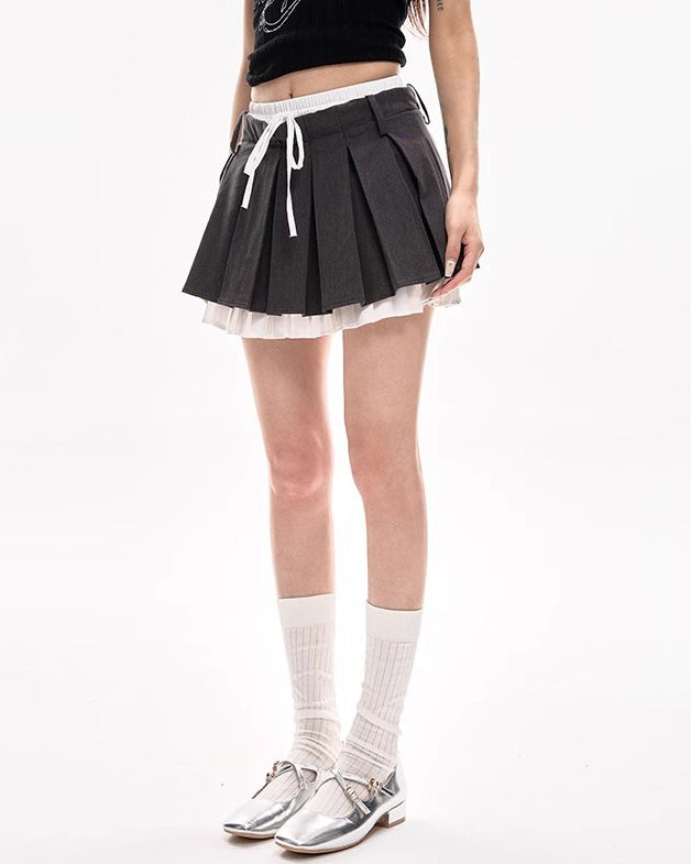 This layered preppy skirt features pleated detailing with a contrast lace underskirt. The ribbon waist and layered construction give it a playful, school-girl vibe- boogzel clothing